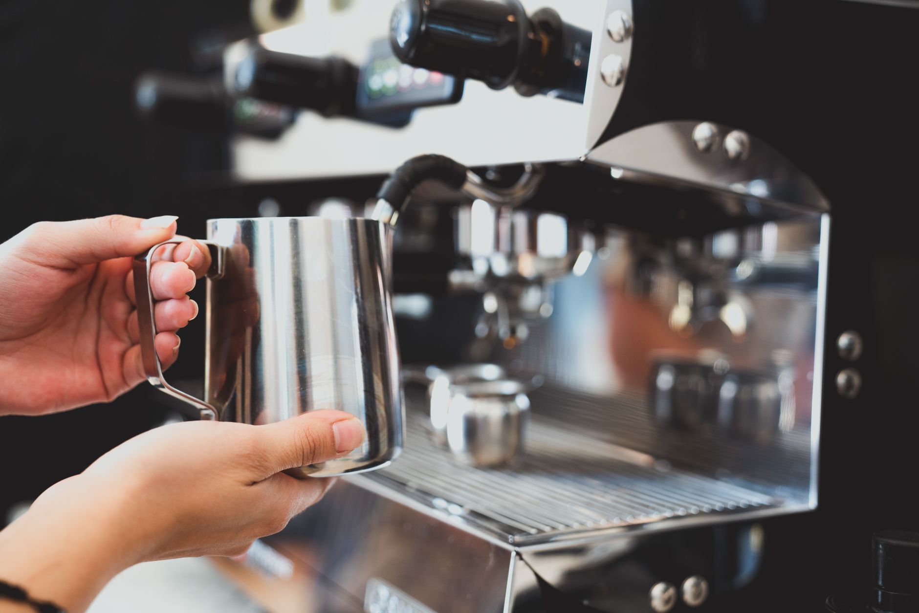 Barista texturing milk in a jug with a steam wand
